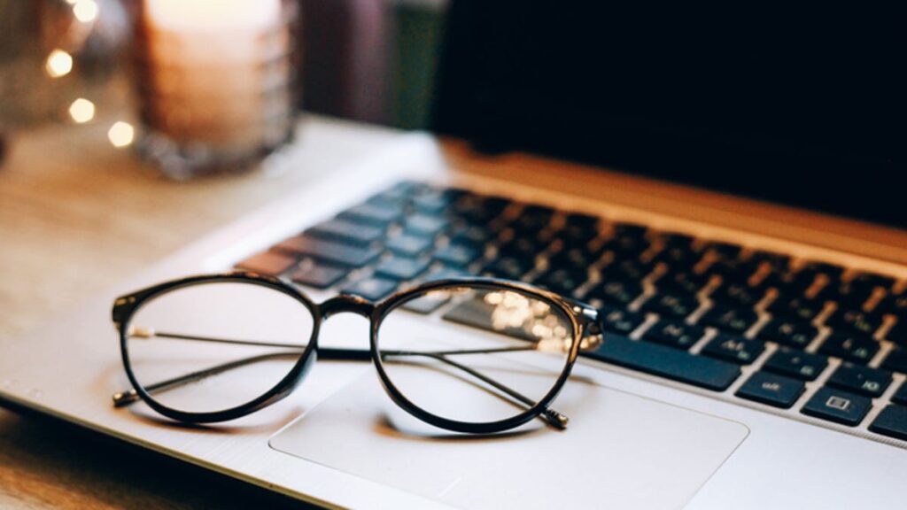 Pair of glasses resting on an open laptop.